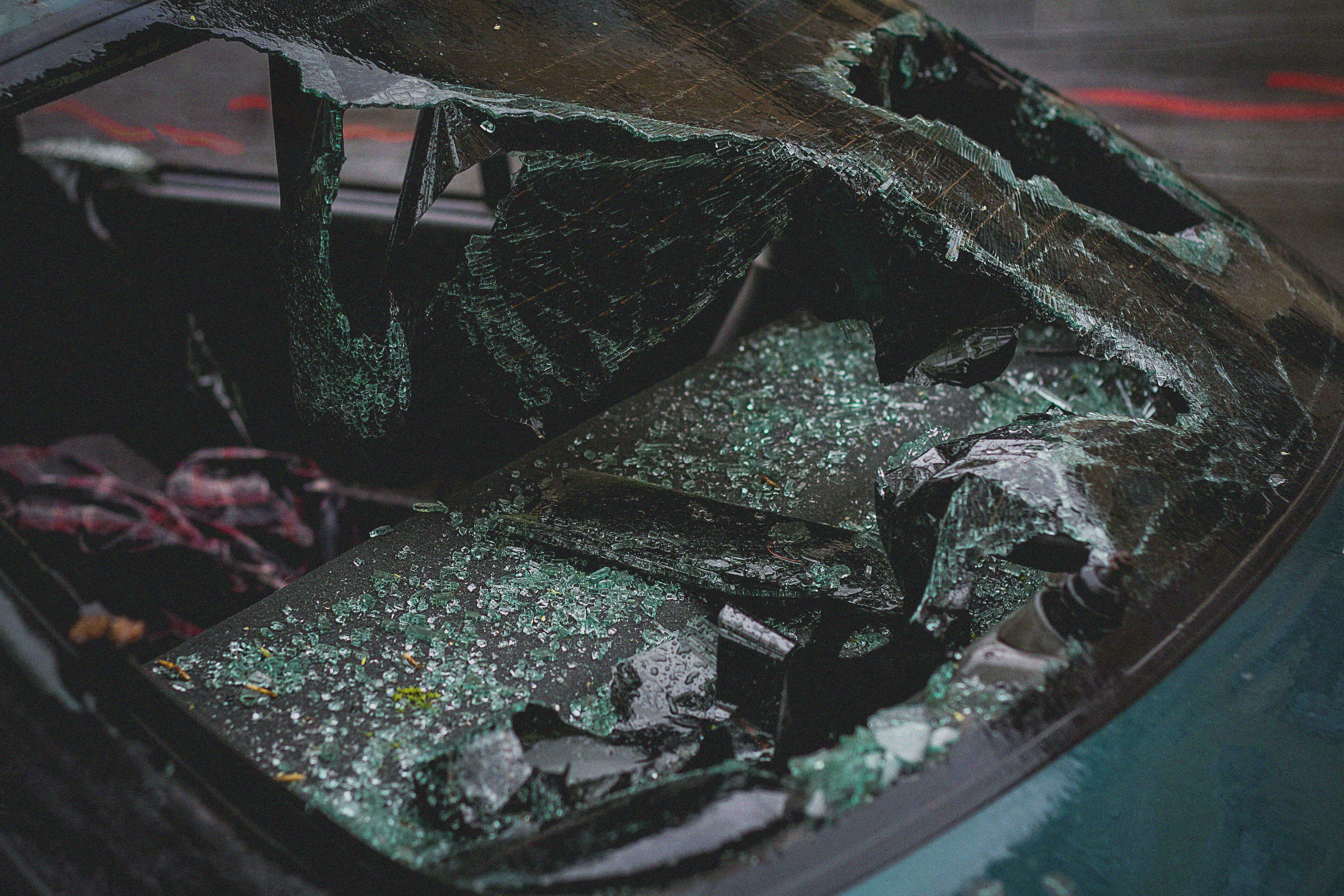 Detailed view of shattered car windshield after accident, emphasizing damage and broken glass.